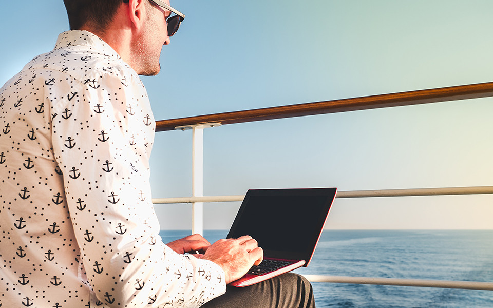 Mann mit Laptop auf Kreuzfahrtschiff